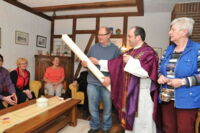 Pfarrer Martin Limberg segnet im Wohnzimmer von Johanna Ellermann (r.) eine Amanduskerze, die Ludwig Köster (l.) hält.
